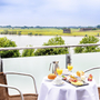 Tisch mit Frühstück auf Balkon mit Flussblick im Hotel in Wesel.