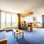 Deluxe-Suite des Welcome Hotel Wesel mit moderner Einrichtung und großen Fenstern.