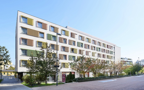 Vorderansicht des JUFA Hotels Wien City mit moderner Fassade und bunten Fensterläden.