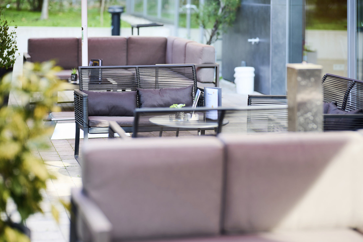 Sitzlounge im Außenbereich des JUFA Hotels Wien City mit Sofas und Tisch.