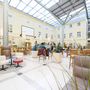 Lichterfüllter Atriumbereich mit Sitzgelegenheiten und Pflanzen im JUFA Hotel Wien City.