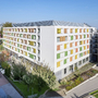Mehrstöckiges Gebäude mit bunten Fensterläden in städtischer Umgebung.