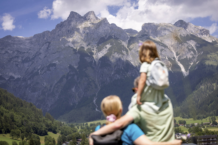 Personen blicken auf eine Berglandschaft in Werfenweng.