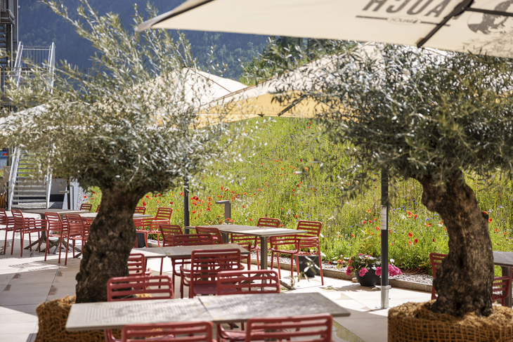 Terrasse des JUFA Hotels in Werfenweng mit Tischen, Stühlen und Sonnenschirmen.