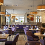 Modernes Restaurant mit gedeckten Tischen und lila Stühlen.