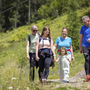 Gruppe von fünf Personen bei sonniger Wanderung in grüner, bergiger Landschaft.