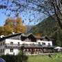 Berghütte umgeben von buntem Herbstwald und Bergen.