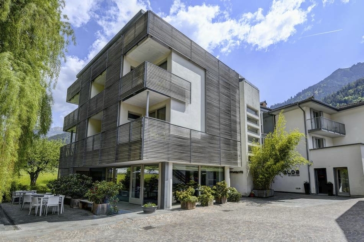Modernes Hotelgebäude in Berglandschaft mit Terrasse und blauen Himmel.