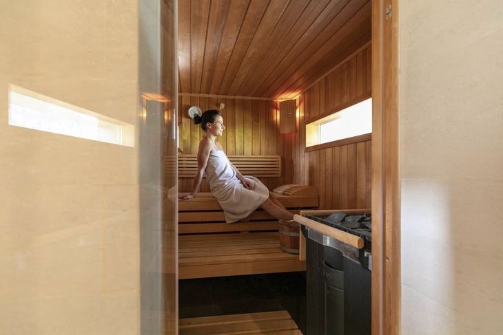 Frau entspannt in einer Sauna mit Holzwänden.