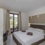 Hotelzimmer mit Doppelbett, Schreibtisch und Balkon mit Blick auf die Berge.