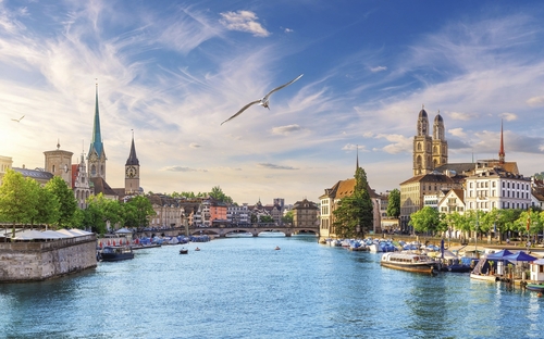 Fluss in Zürich mit historischen Gebäuden und blauen Himmel.