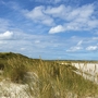 Leuchtturm auf einer Düne am Strand von Sylt unter blauem Himmel mit Wolken.