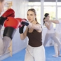 Eine Frau und ein Mann trainieren Boxverteidigung in einem Fitnessstudio.