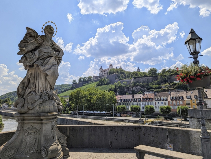 Blick auf Festung Marienberg in Würzburg mit Skulptur und Brücke im Vordergrund.