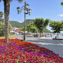 Uferpromenade am See mit bunten Blumenbeeten und Laternen.