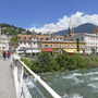 Innenstadt von Meran mit Fluss und Bergen im Hintergrund.