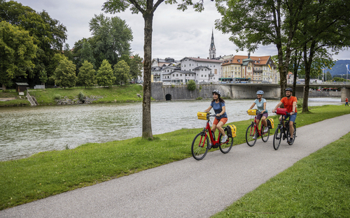 Radfahrer an der Isar in Bad Tölz auf Radweg unter Bäumen.