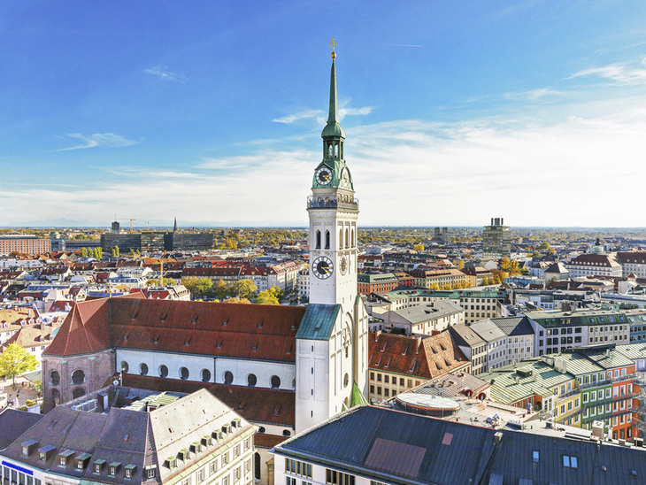 Blick auf die Kirche St. Peter in der Münchner Innenstadt unter blauem Himmel.