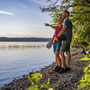 Paar macht Radtour-Pause am Starnberger See auf Kiesstrand bei schönem Wetter.