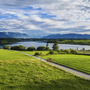 Radfahrer auf einem Weg am Riegsee vor Bergkulisse und Wiesenlandschaft.
