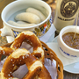 Weißwürste, Brezeln, süßer Senf und Bierkrug auf einem Holztisch.