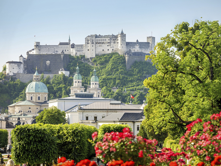 Festung Hohensalzburg in Salzburg mit blühenden Gärten im Vordergrund.