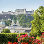 Festung Hohensalzburg in Salzburg mit blühenden Gärten im Vordergrund.