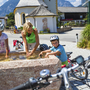 Radfahrer machen Pause an einem Brunnen bei Sonnenschein.