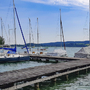 Segelboote an einem Steg auf einem See bei sonnigem Wetter.