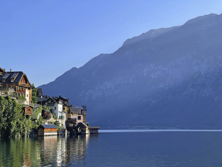 Häuser am Seeufer in Hallstatt vor bewaldeten Bergen im Hintergrund.