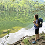 Frau wandert am Ufer des Nussensees, umgeben von Wald und reflektierendem Wasser.