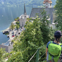 Person wandert auf einem Pfad hinab nach Hallstatt mit Blick auf den See und Kirche.