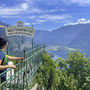 Person betrachtet Aussichtspunkt über See und Berge im Salzkammergut bei Sonnenschein.