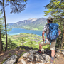 Wanderer mit Rucksack blickt auf den Wolfgangsee im Salzkammergut, umgeben von Bergen.
