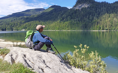 Wanderer sitzt mit Rucksack am Ufer des Schwarzensees im Salzkammergut.