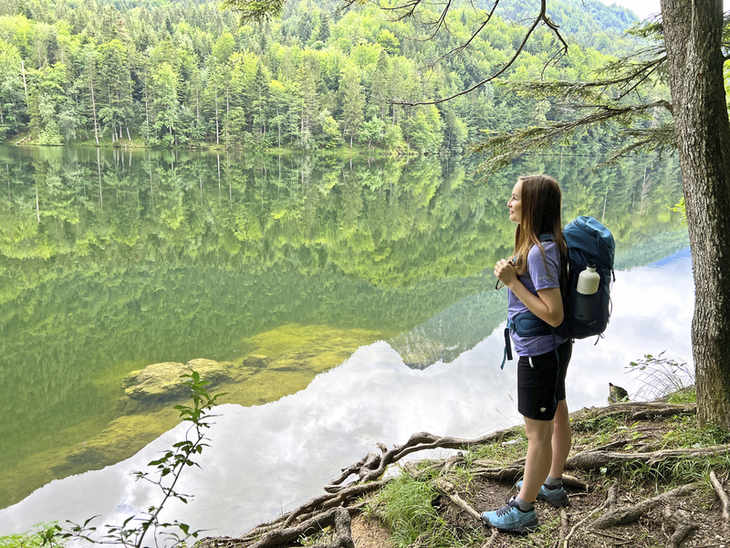 Wanderer blickt auf den Nussensee, umgeben von Wald und ruhigem Wasser.