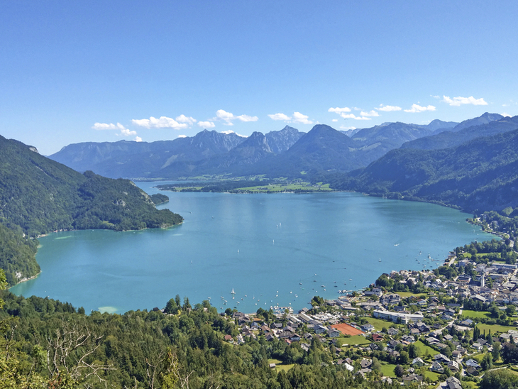 Blick auf den Wolfgangsee im Salzkammergut mit umliegenden Bergen und Dörfern.