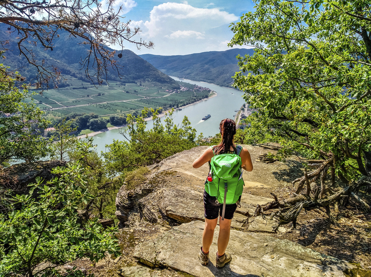 Wanderer mit grünem Rucksack blickt auf die Donau in der Wachau.