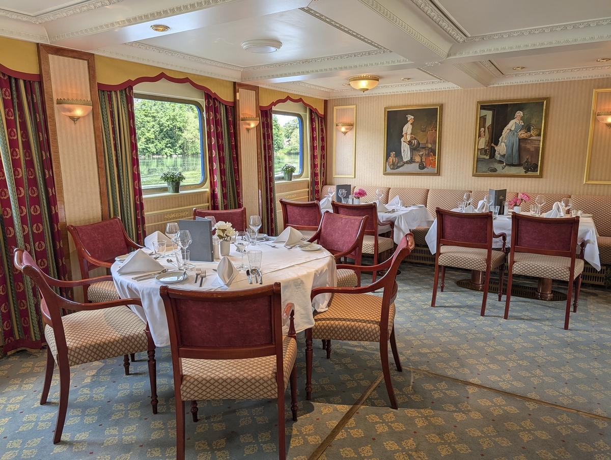 Elegantes Restaurant auf einem Schiff mit gedeckten Tischen und Gemälden.