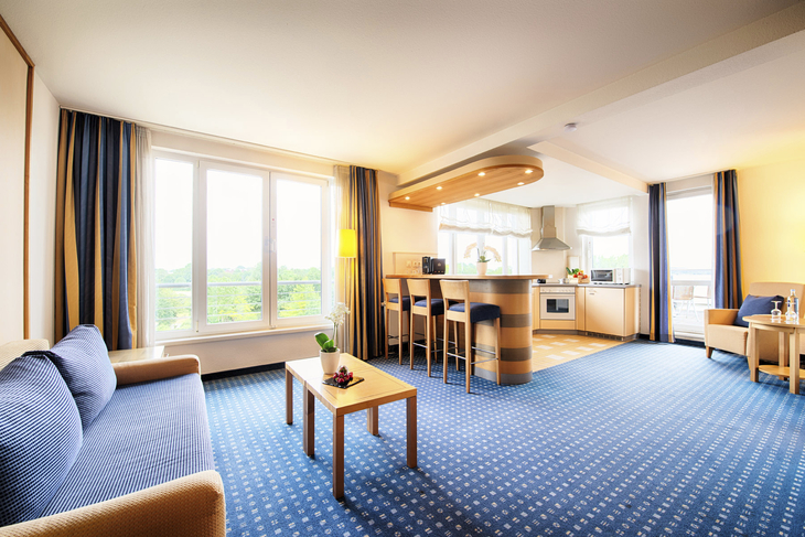 Deluxe-Suite des Welcome Hotel Wesel mit moderner Einrichtung und großen Fenstern.