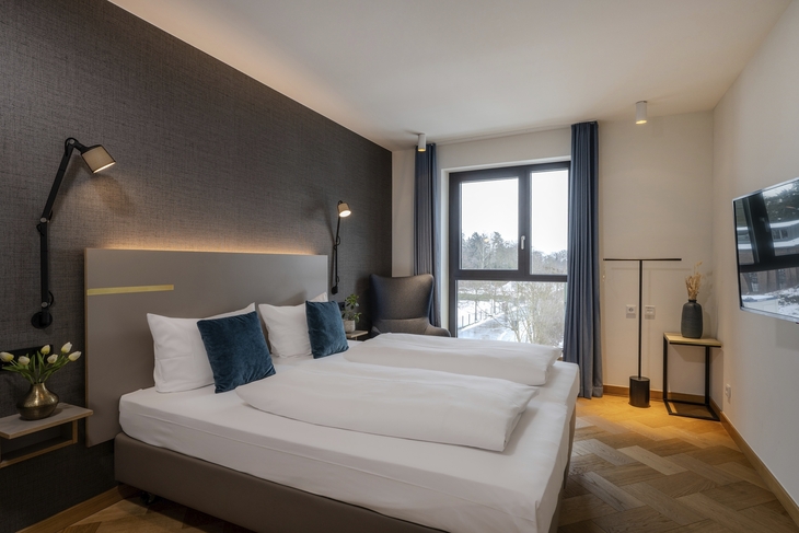 Hotelzimmer mit Doppelbett, Fenster, Fernseher und moderner Einrichtung.