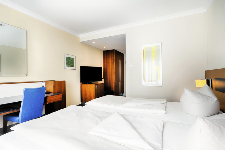 Doppelzimmer mit Schreibtisch, TV und moderner Einrichtung in einem Hotel.
