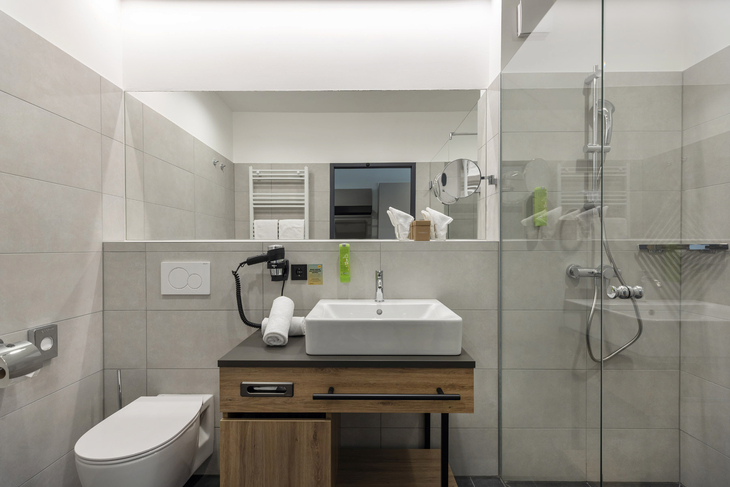 Modernes Hotelbadezimmer mit Waschbecken, Dusche und WC.