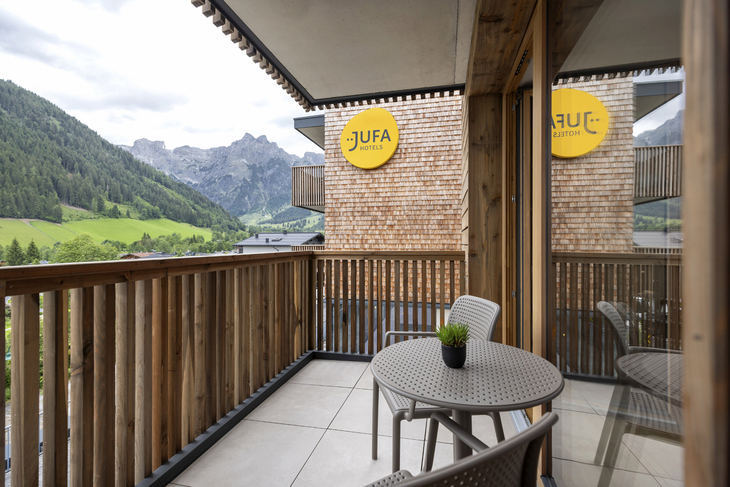 Balkonansicht des JUFA Hotels in Werfenweng, mit Bergpanorama und Sitzmöbeln.