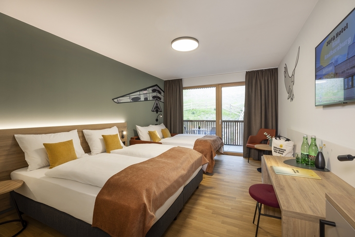 Hotelzimmer mit zwei Betten, moderner Einrichtung und Balkonblick.
