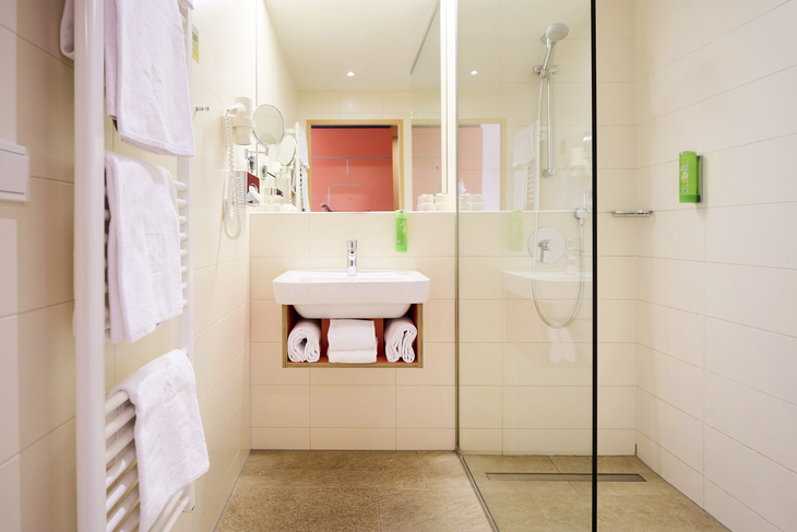Modernes Hotelbadezimmer mit Dusche und Waschbecken im JUFA Hotel Wien City.