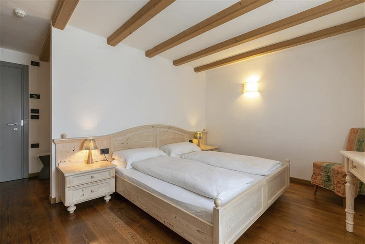 Holzvertäfeltes Hotelzimmer mit Doppelbett und Nachttischen.