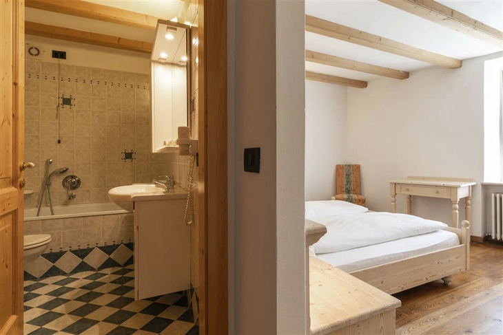 Blick in ein Hotelzimmer mit Bett, Schreibtisch und Blick ins Badezimmer.