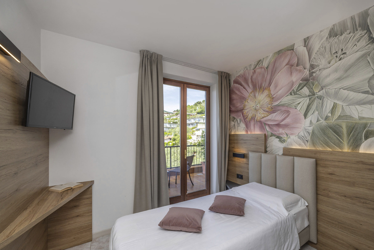 Einzelzimmer in einem Hotel mit Balkon, Blumenmotiv an der Wand.