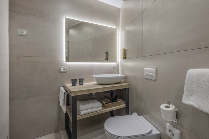 Modernes Badezimmer mit beleuchtetem Spiegel, Waschtisch und WC.